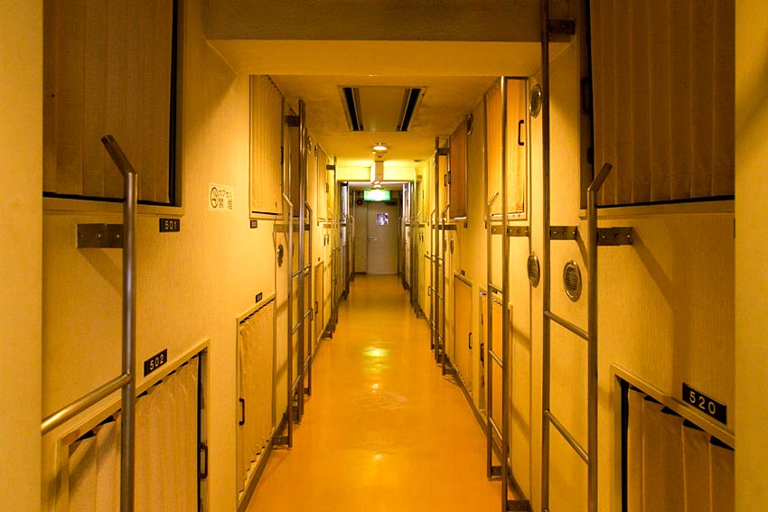 Capsule corridor with a low ceiling and floor lighting at the base.